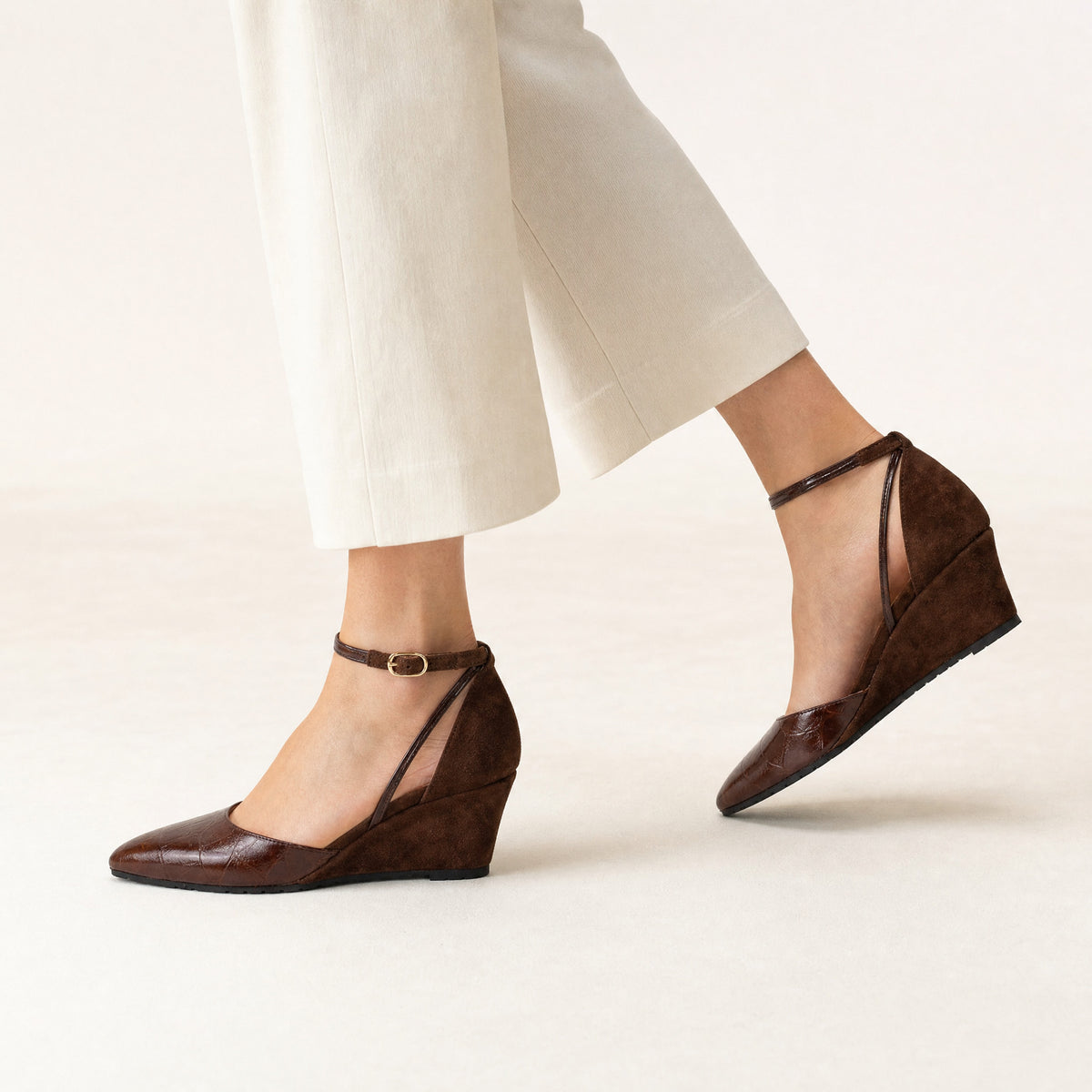 Woman walking in Landmark Cocoa brown croc and suede wedges with cropped ivory trousers, worn on foot